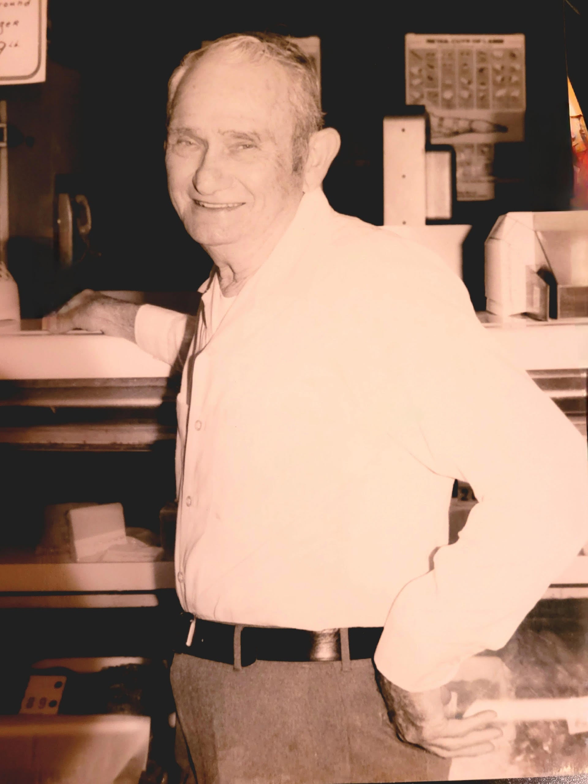 A sepia photograph of an older Bill Gerstman at a store, smiling into the camera.
